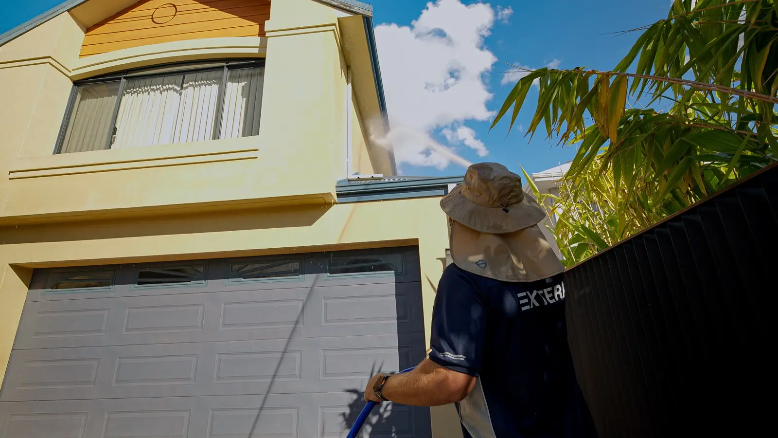 Extera operator soft washing a two-storey Perth home